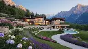 A very luxurious house nestled in the mountains, surrounded by a magnificent garden bursting with vibrant flowers. The property includes a spacious parking lot and a sparkling swimming pool, all set against the b.webp